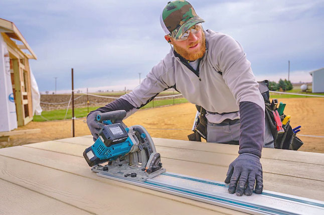 Construction worker using a saw to cut engineered wood panels to size.
